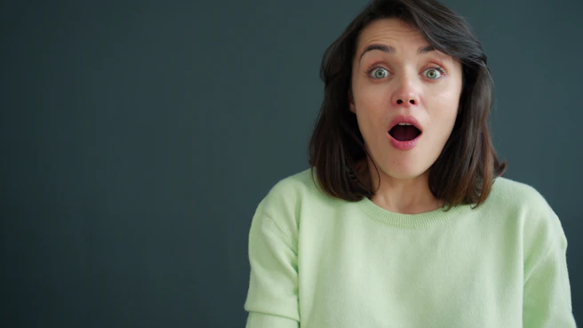 Woman with surprised expression against dark background