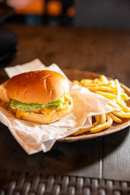 A juicy burger with fries on a wooden plate