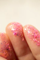 Pink glitter on fingers with a soft background
