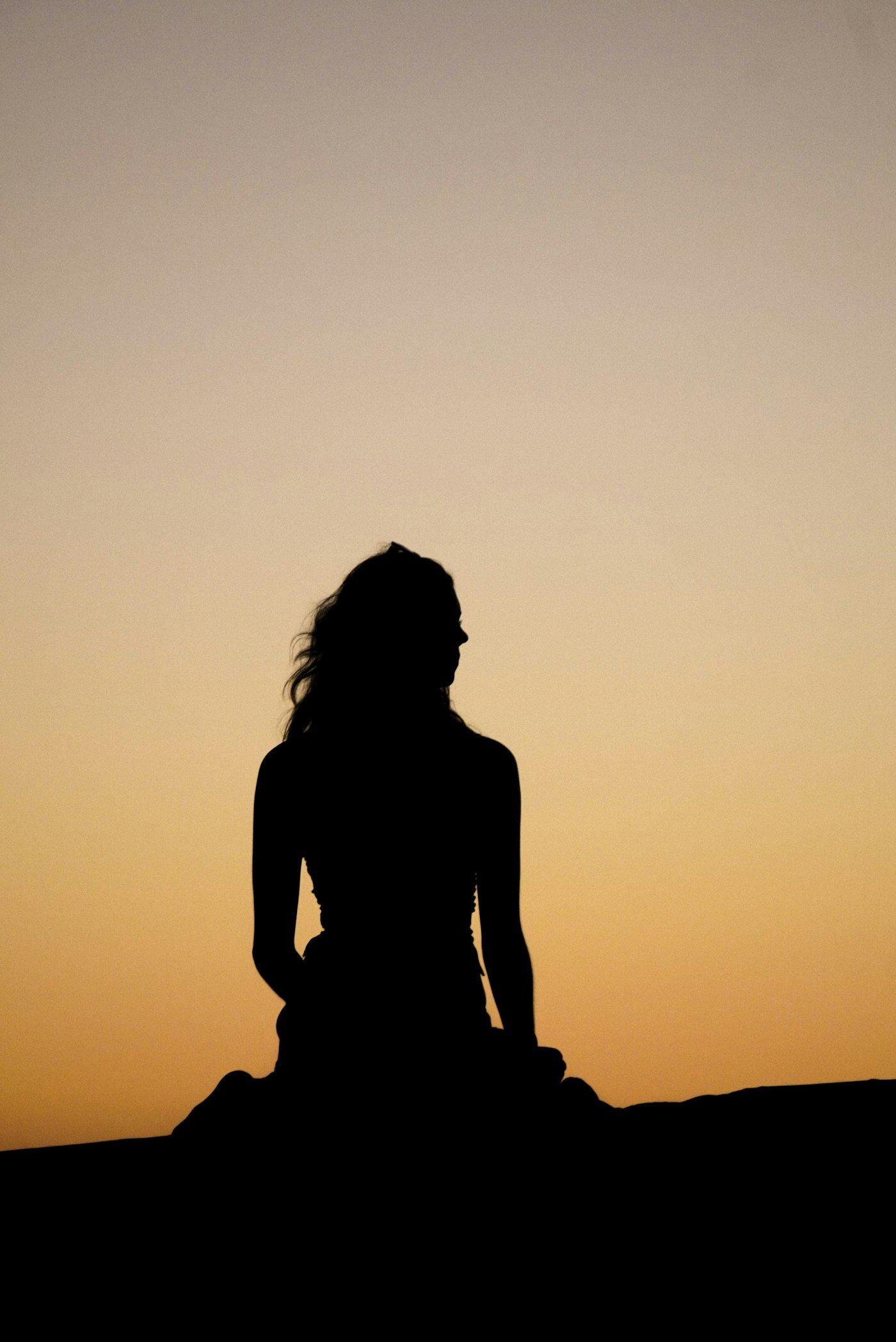 Woman silhouette against a sunset sky, contemplative and peaceful