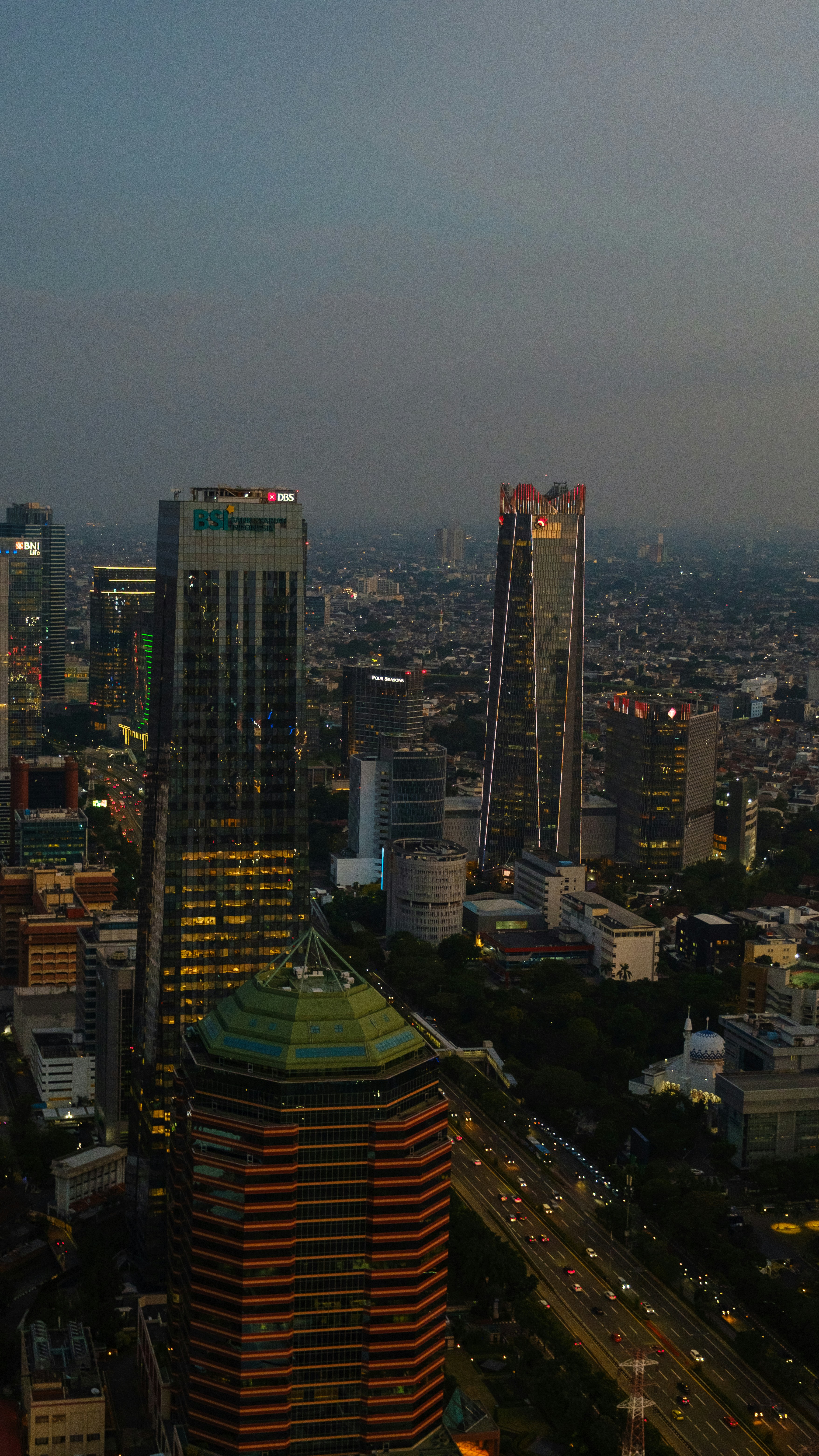 Paysage urbain avec des gratte-ciel illuminés et une autoroute très fréquentée au crépuscule