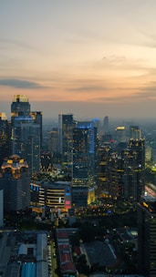 Modern cityscape with illuminated skyscrapers at dusk.
