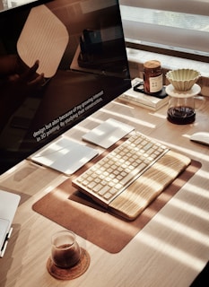 Wooden desk with keyboard, coffee, and monitor.