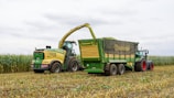 Harvester loading corn into a trailer in a field.