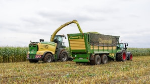 Harvester loading corn into a trailer in a field.