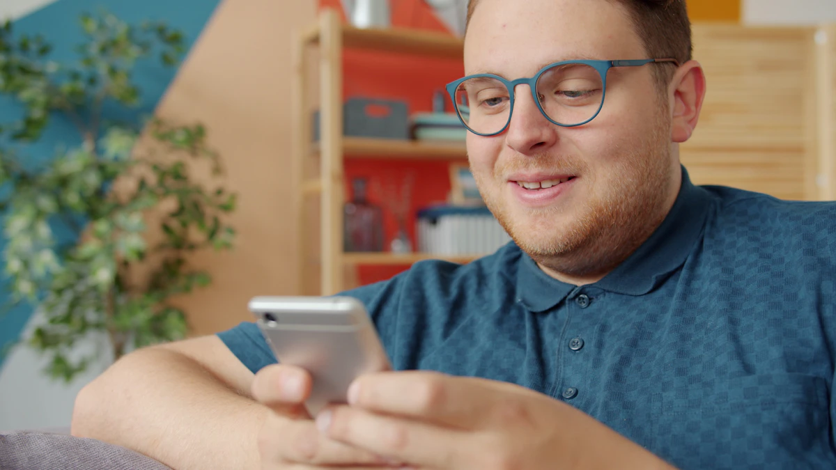 Man smiling while texting on his smartphone