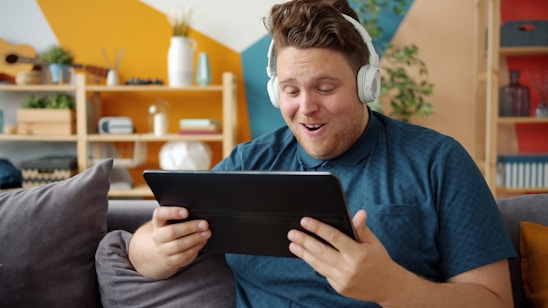 Man wearing headphones watching tablet with surprise