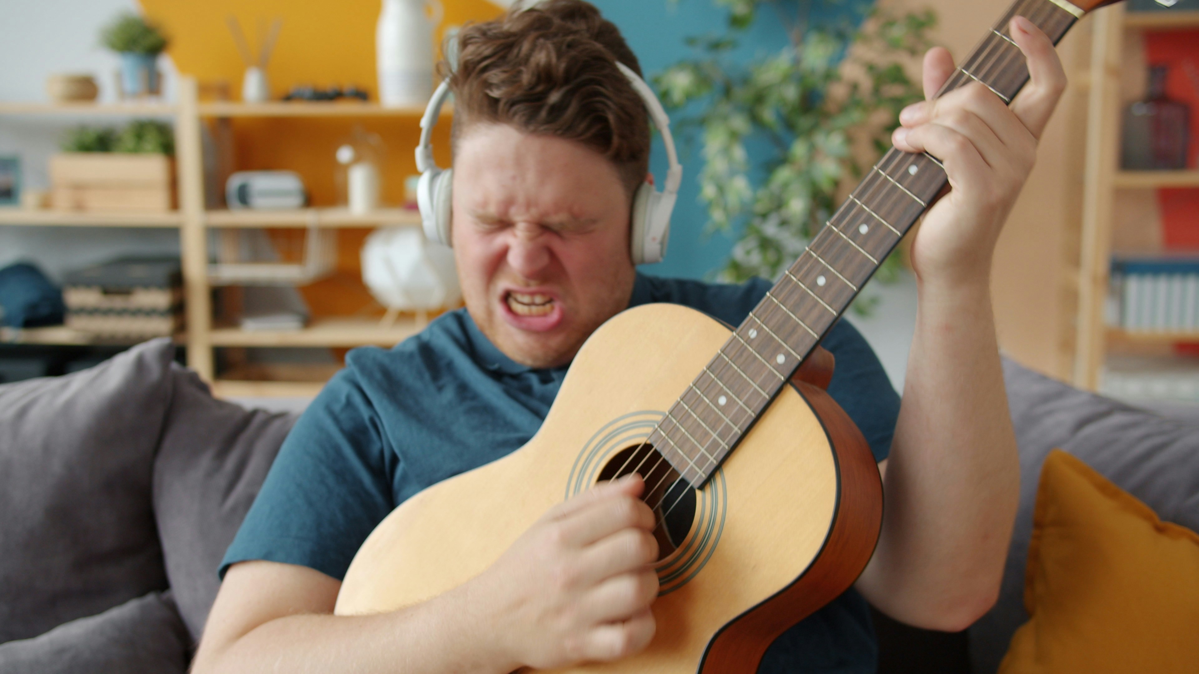 Creative guy playing guitar with headphones