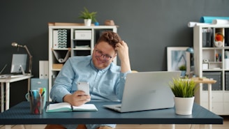 Man laughing while looking at his phone at desk.