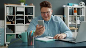Man smiling while looking at his phone at desk