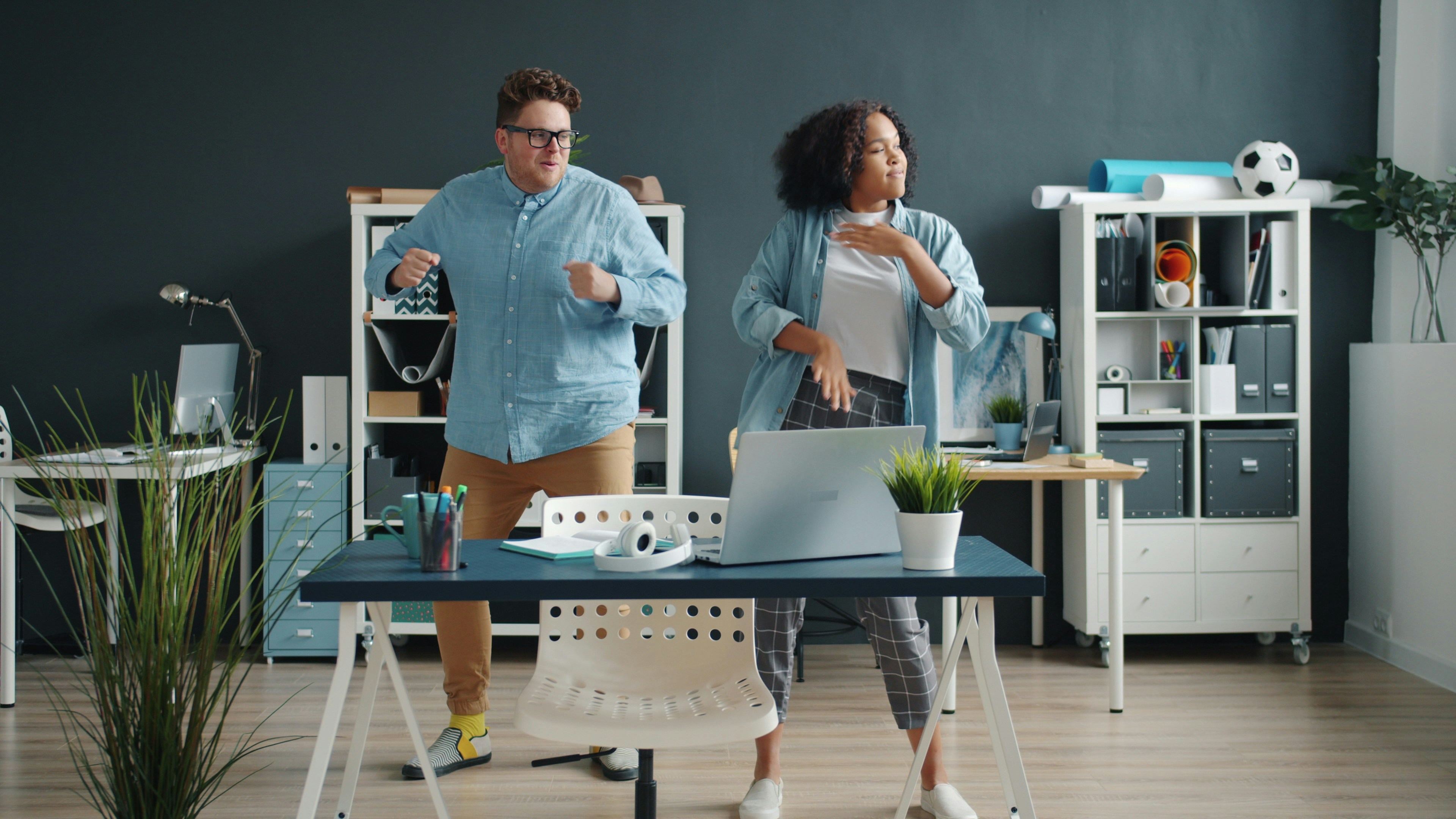 10 Easy Ways to Incorporate More Movement Into Your Workday – Two colleagues dancing energetically in a modern office.