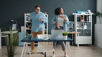 Two colleagues dancing energetically in a modern office.