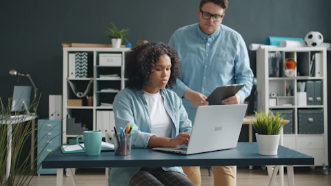 Two colleagues working together at a desk.