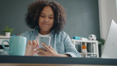 Young girl using a smartphone at a desk.