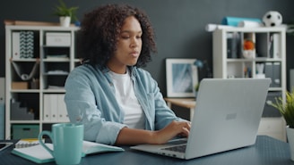 Young woman working on a laptop at a desk.