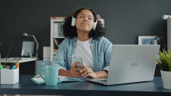 Young woman listening to music with headphones at desk