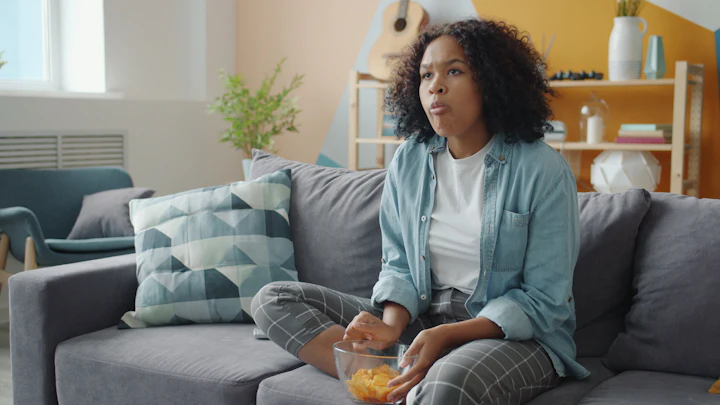 A woman eating crisps in front of the TV