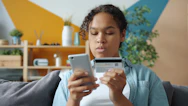 Woman holding credit card and phone for online shopping.