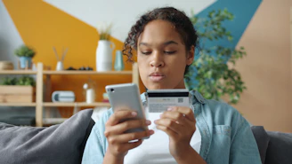 Woman holding credit card and phone for online shopping.