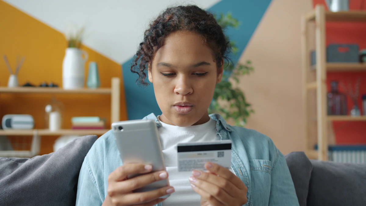 Perempuan memegang kartu bank dan ponsel untuk transaksi daring.