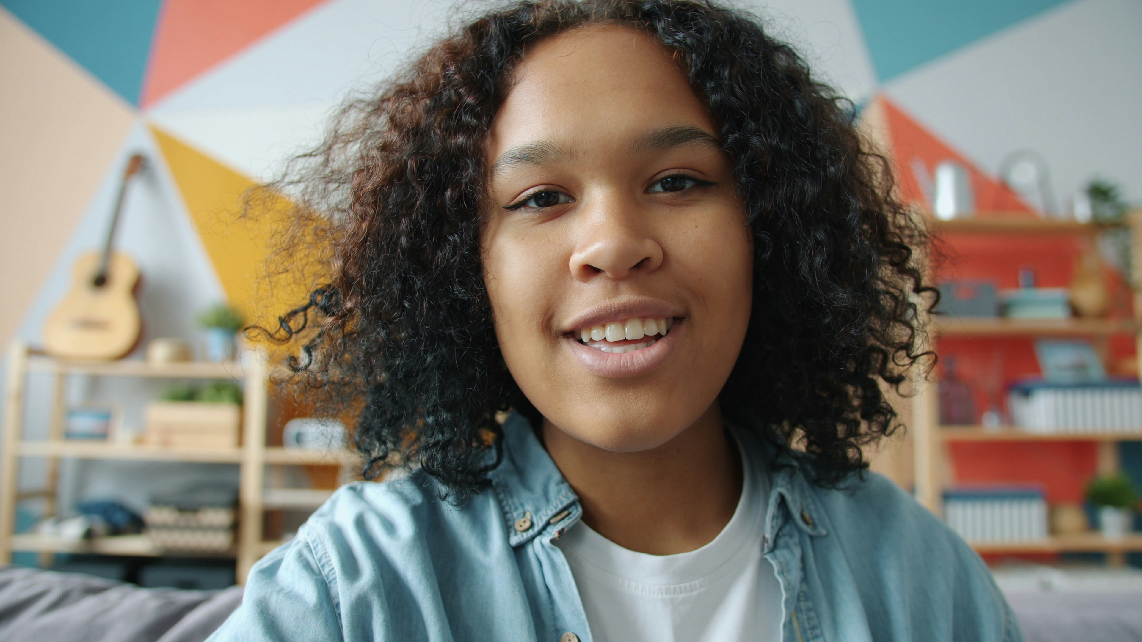 Young woman with curly hair smiling at the camera.
