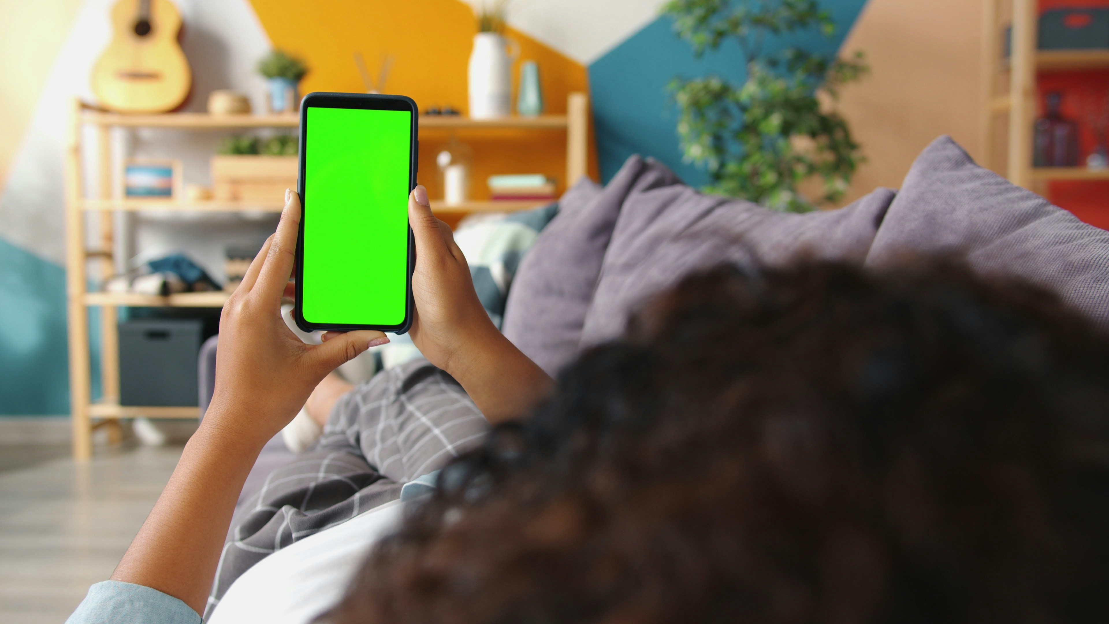 Person holding a smartphone with a green screen.