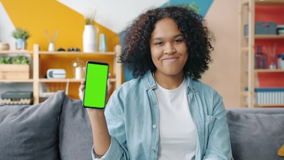 Young woman holding a smartphone with a green screen.