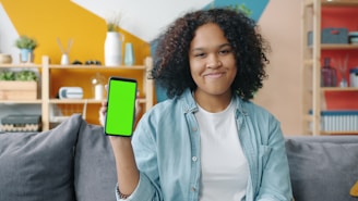 Young woman holding a smartphone with a green screen.