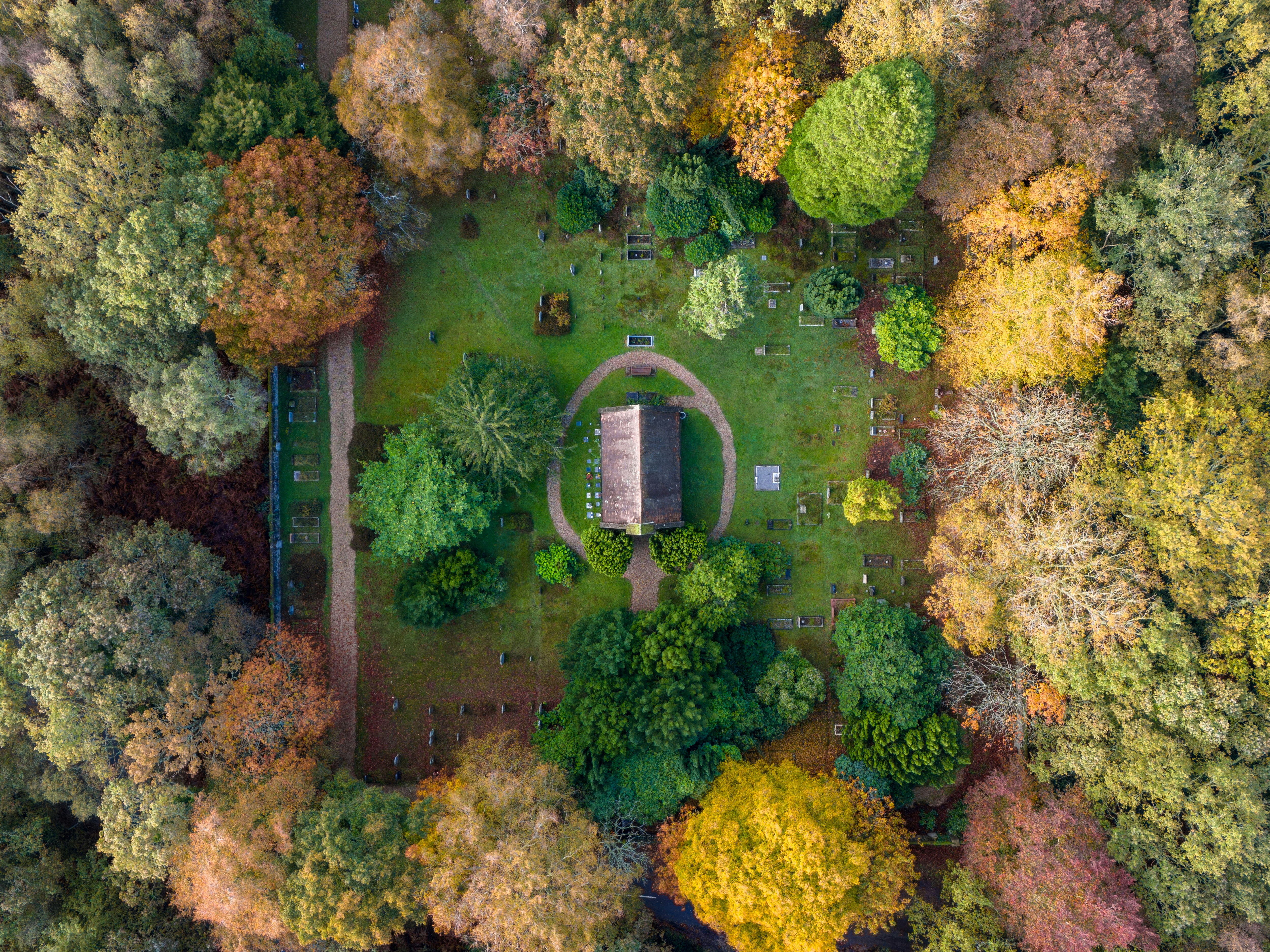 Aerial view of a small church surrounded by autumn trees.
