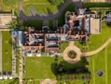 Aerial view of a large historic manor house with gardens.