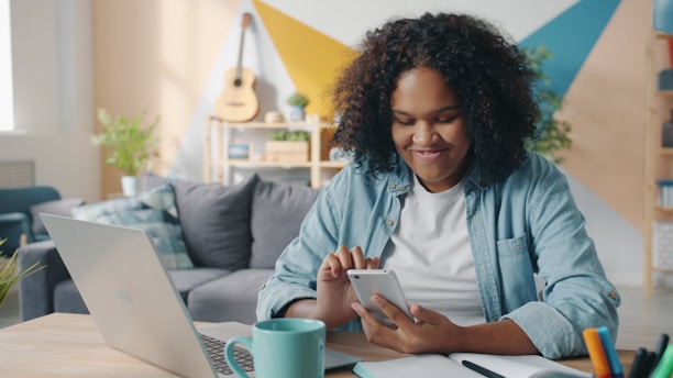 Young woman smiling while using her smartphone at desk.