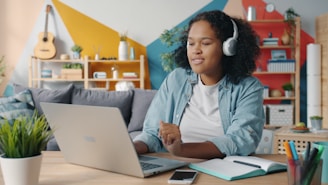 Young woman wearing headphones works on a laptop.