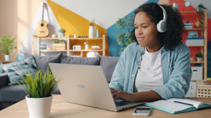 Young woman wearing headphones using laptop at desk
