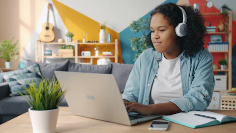 Young woman wearing headphones using laptop at desk.