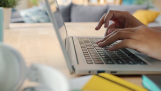 Hands typing on a laptop keyboard at a desk.