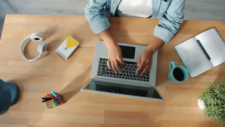 Person typing on a laptop at a wooden desk.