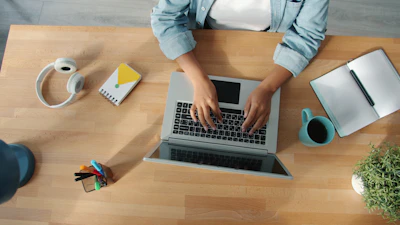 Person typing on a laptop at a wooden desk.