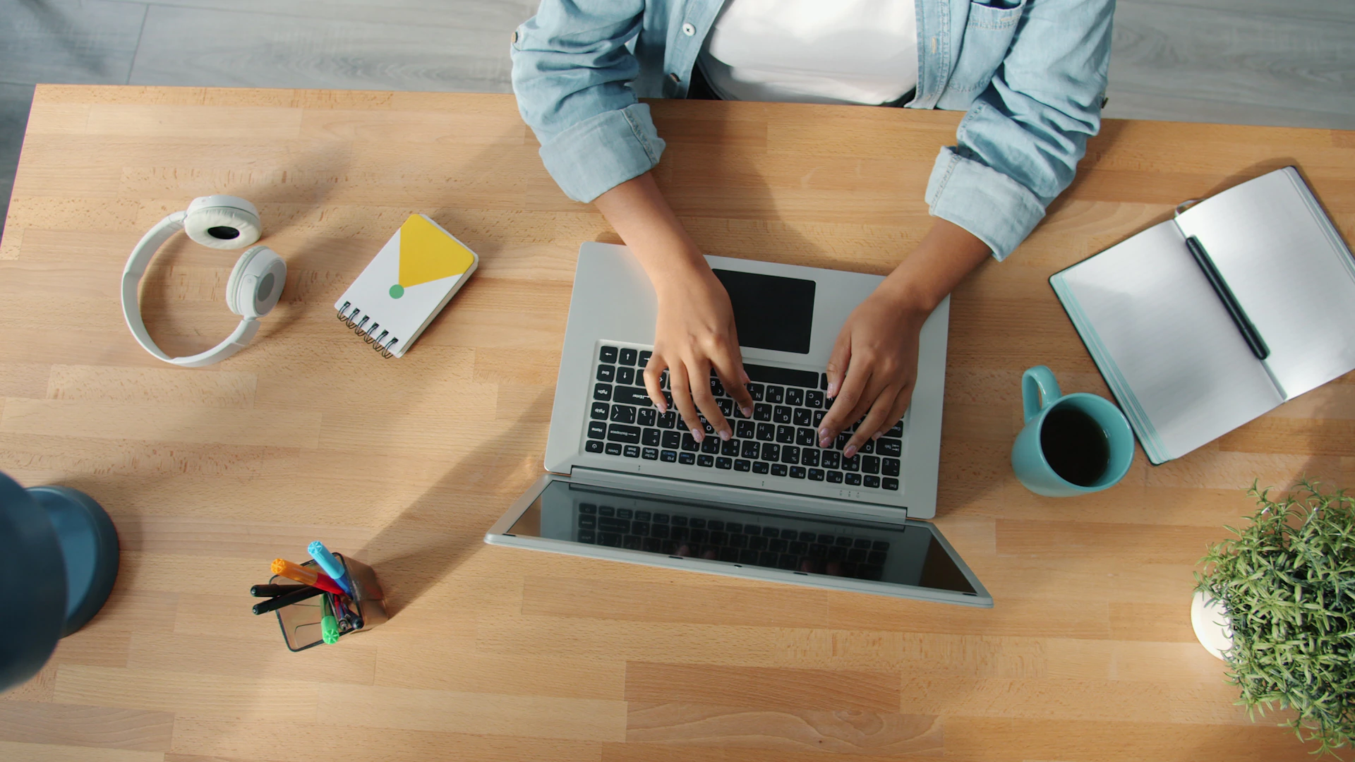 Person typing on a laptop at a wooden desk.