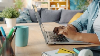 Person typing on a laptop at a wooden desk.