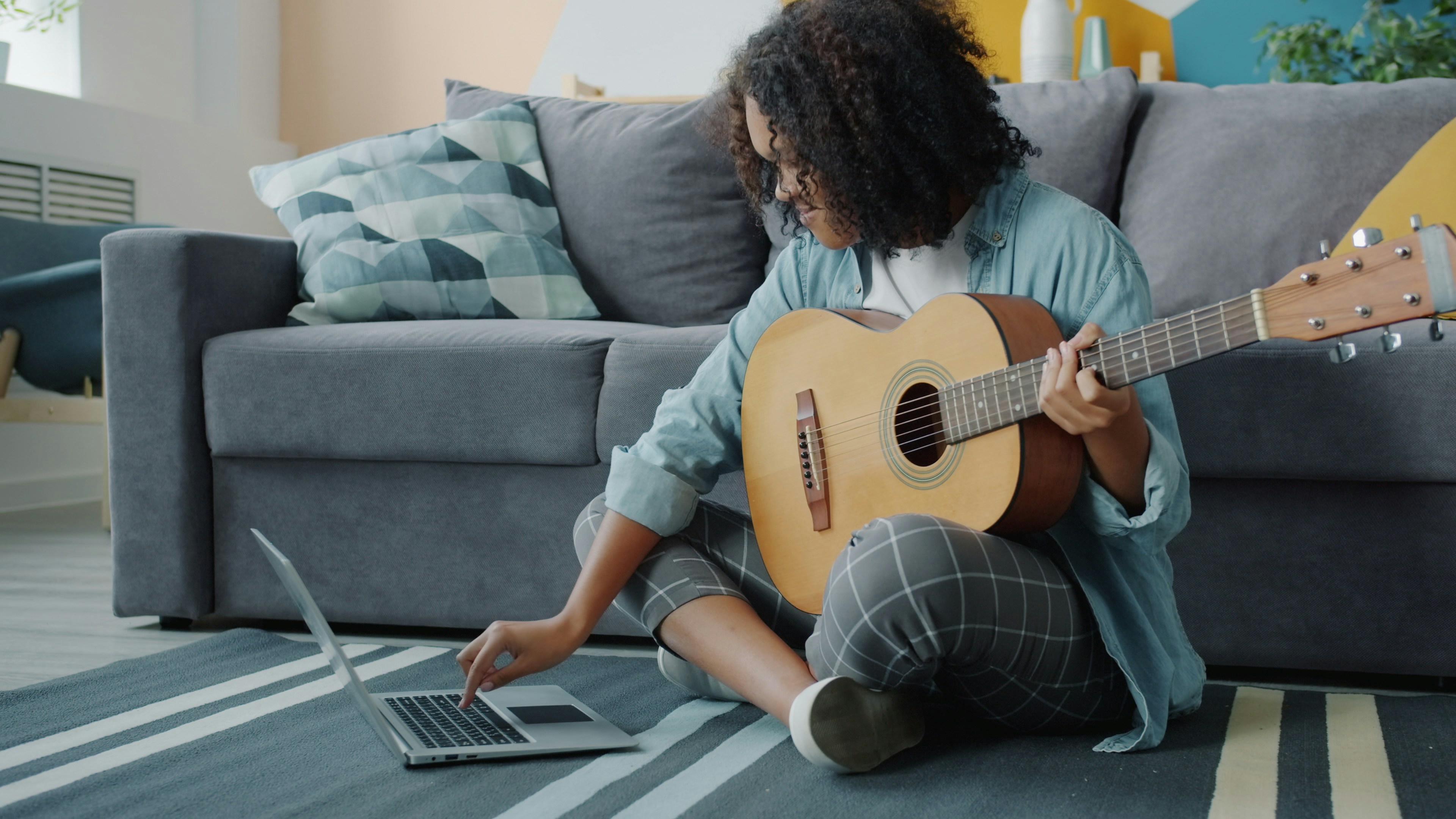 Lady learning guitar with laptop tutorial
