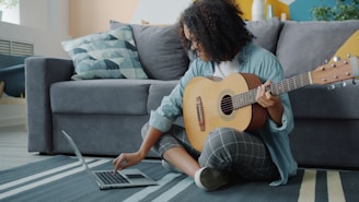 Woman learning guitar from laptop at home