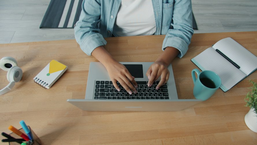 Person typing on a laptop keyboard in a dimly lit home office