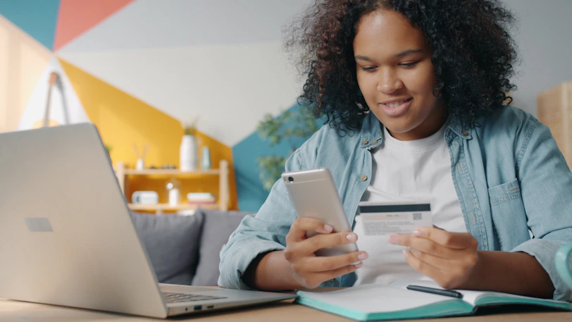 Teenager using phone and credit card for online shopping