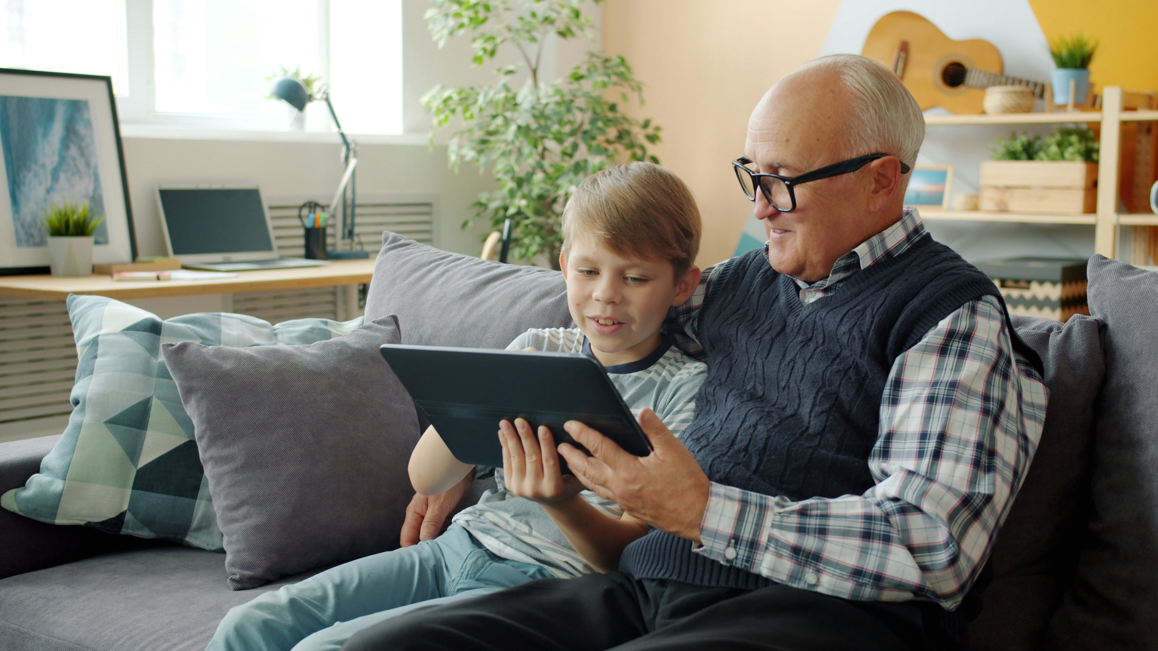 Grandfather and grandson looking at tablet on tablet.