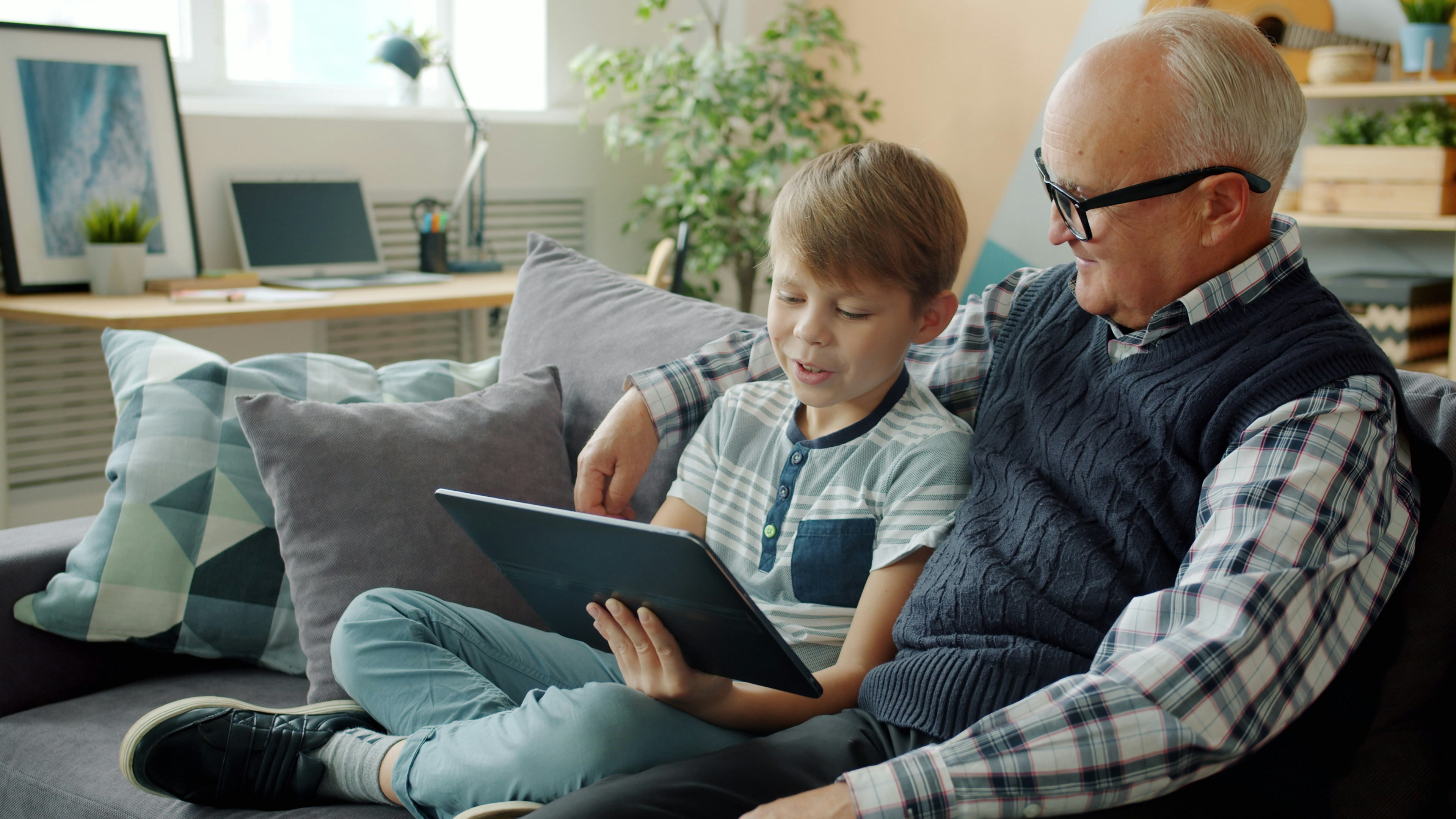 Grandfather and grandson looking at a tablet together.