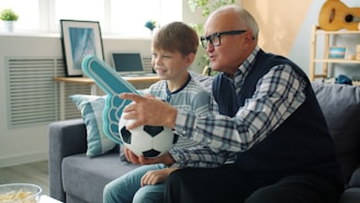 Grandfather and grandson watching soccer game with ball.