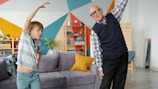Grandfather and grandson exercising together indoors.