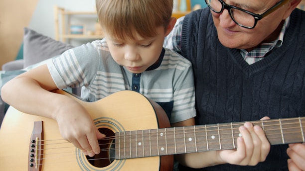Grandfather teaching grandson to play guitar