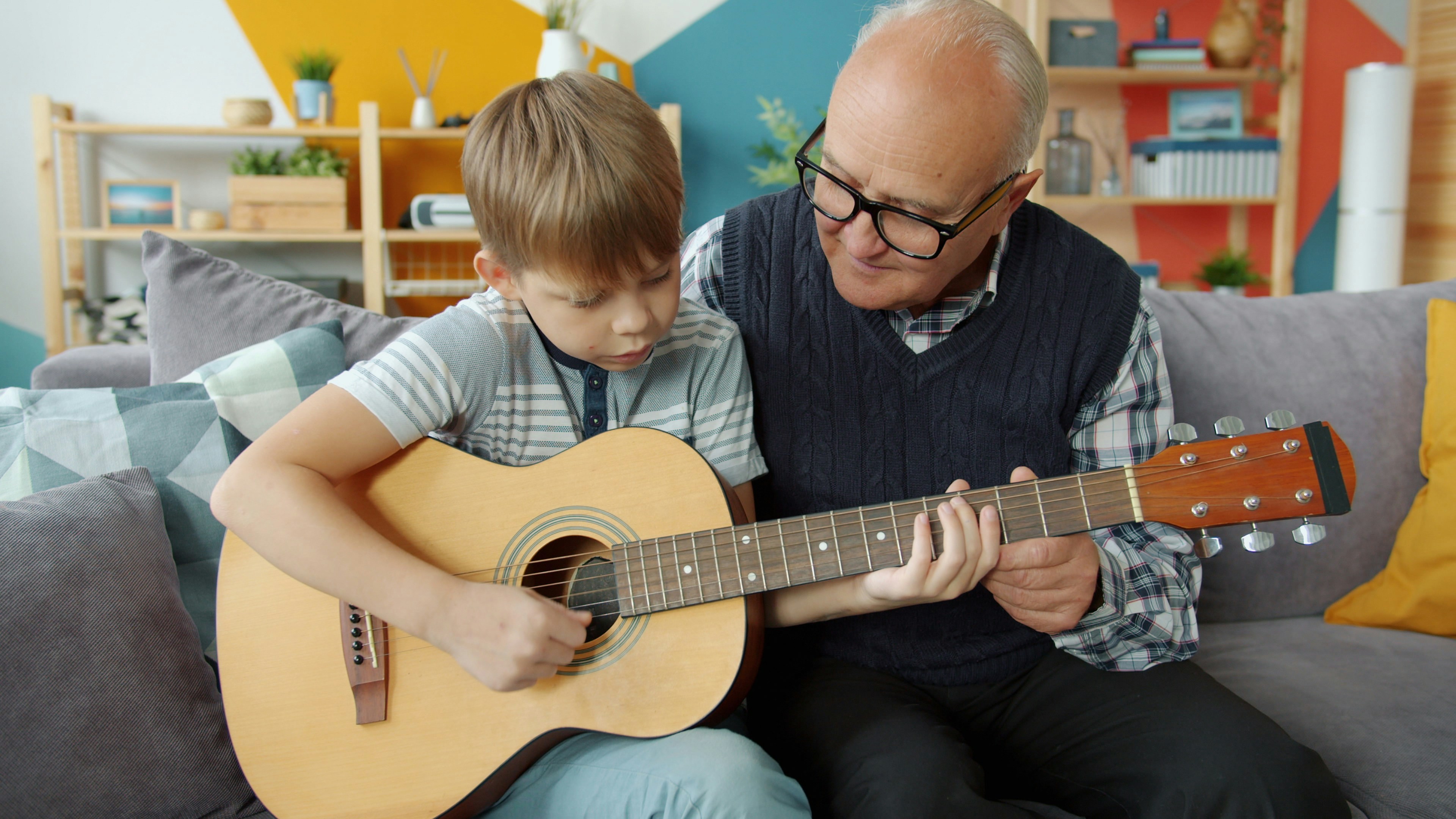 Grandfather teaching grandson to play guitar