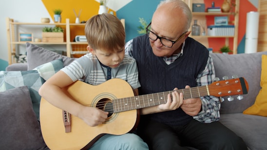 Grandfather teaching grandson to play guitar